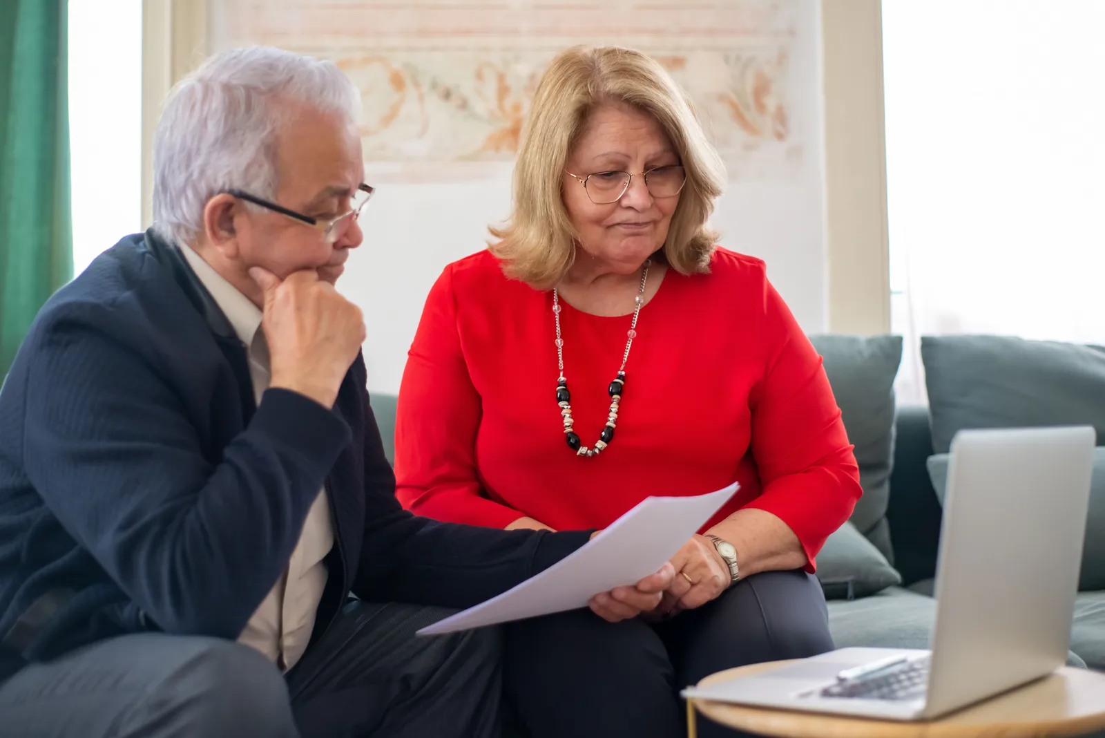 Elderly couple reviewing financial documents together at home in Portugal.